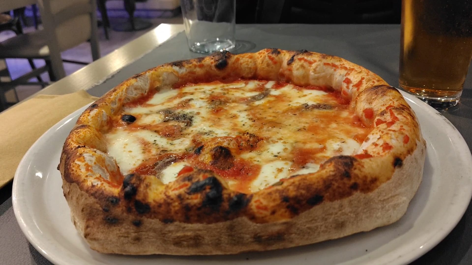 Neapolitan pizza with melted cheese and fresh herbs on a white plate